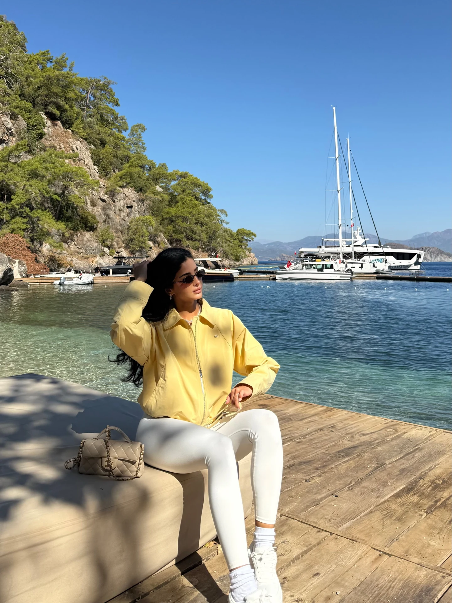 Rahaf Alharbi in a yellow Alo zip-up top and white leggings beside the water at Yazz Collective