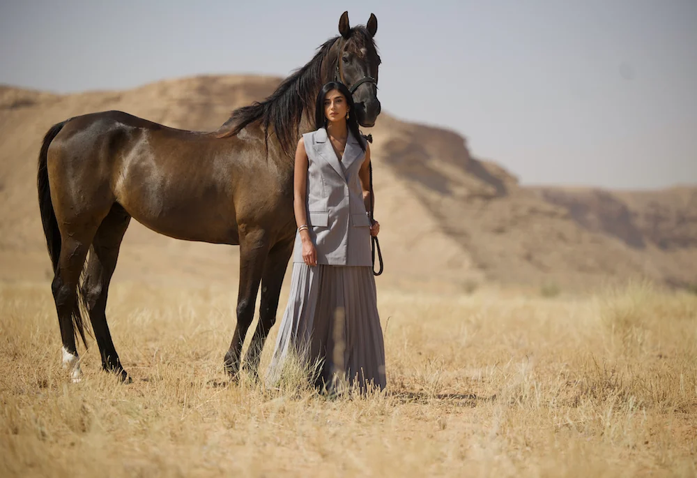 Rahaf beside a dark horse in the photograph accompanying her Luxury Network interview