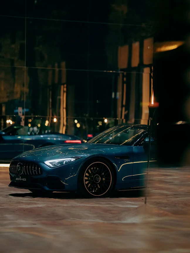 A Mercedes-Benz photographed against city lights at night