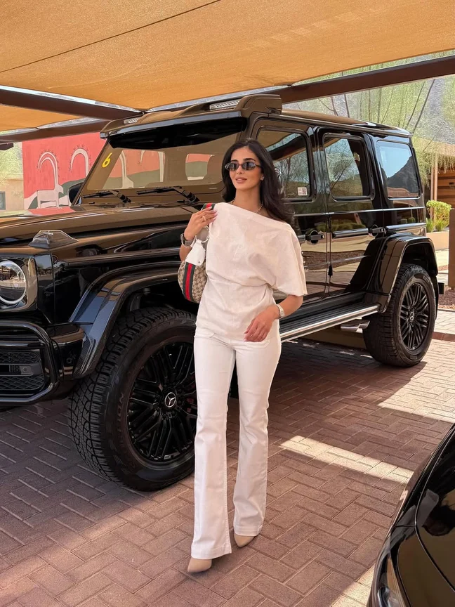 Rahaf in white beside a black Mercedes-Benz G-Class