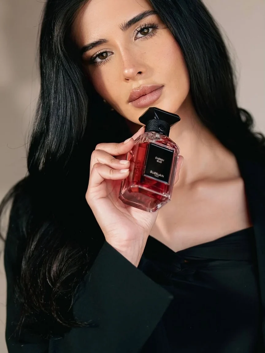 Guerlain red perfume bottle held near face