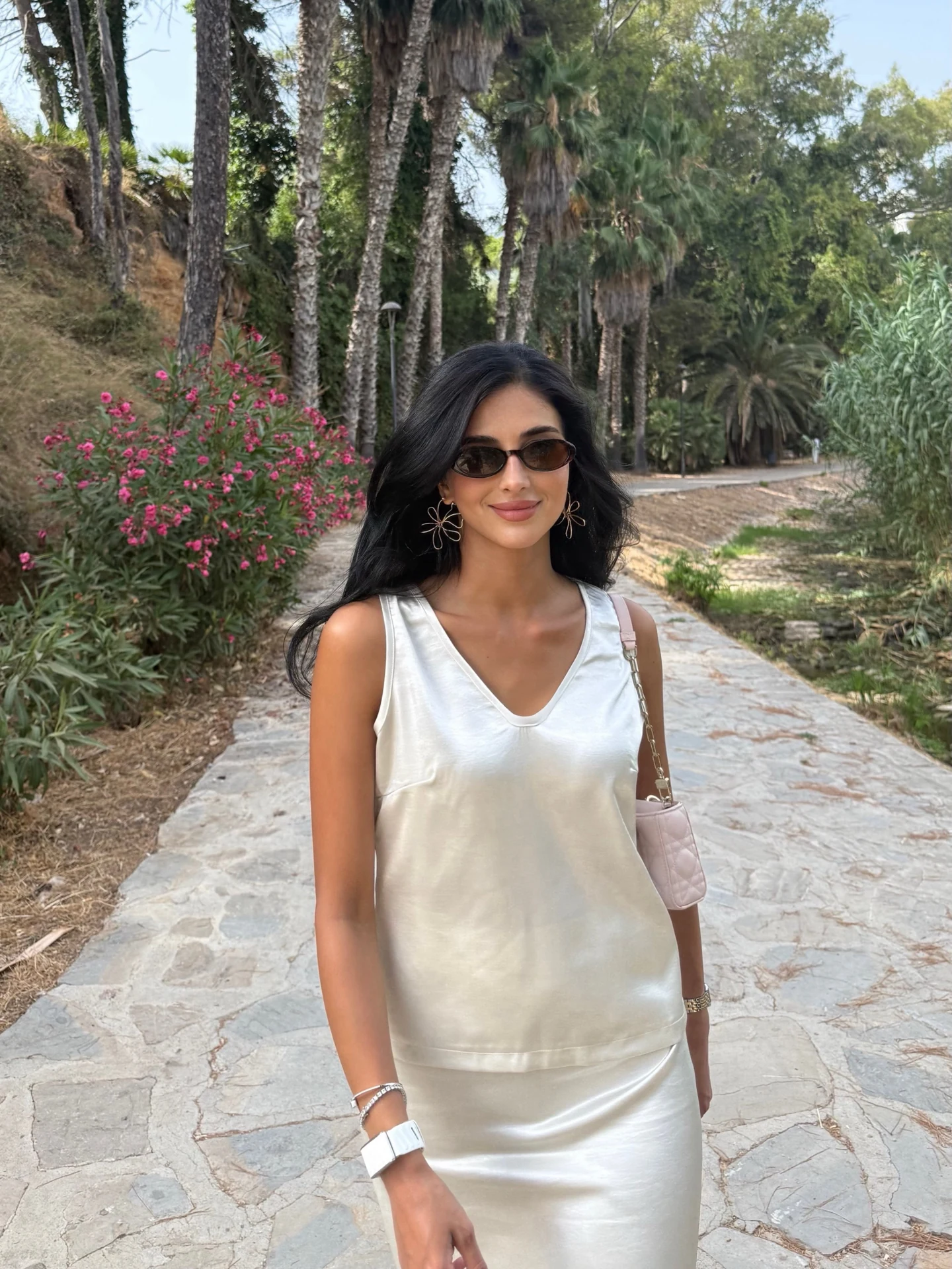 Rahaf in an ivory sleeveless dress on a garden path