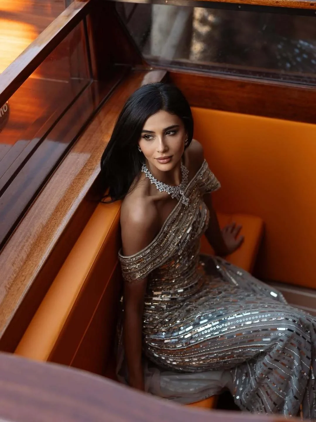 Rahaf seated in a wooden boat in her silver evening gown