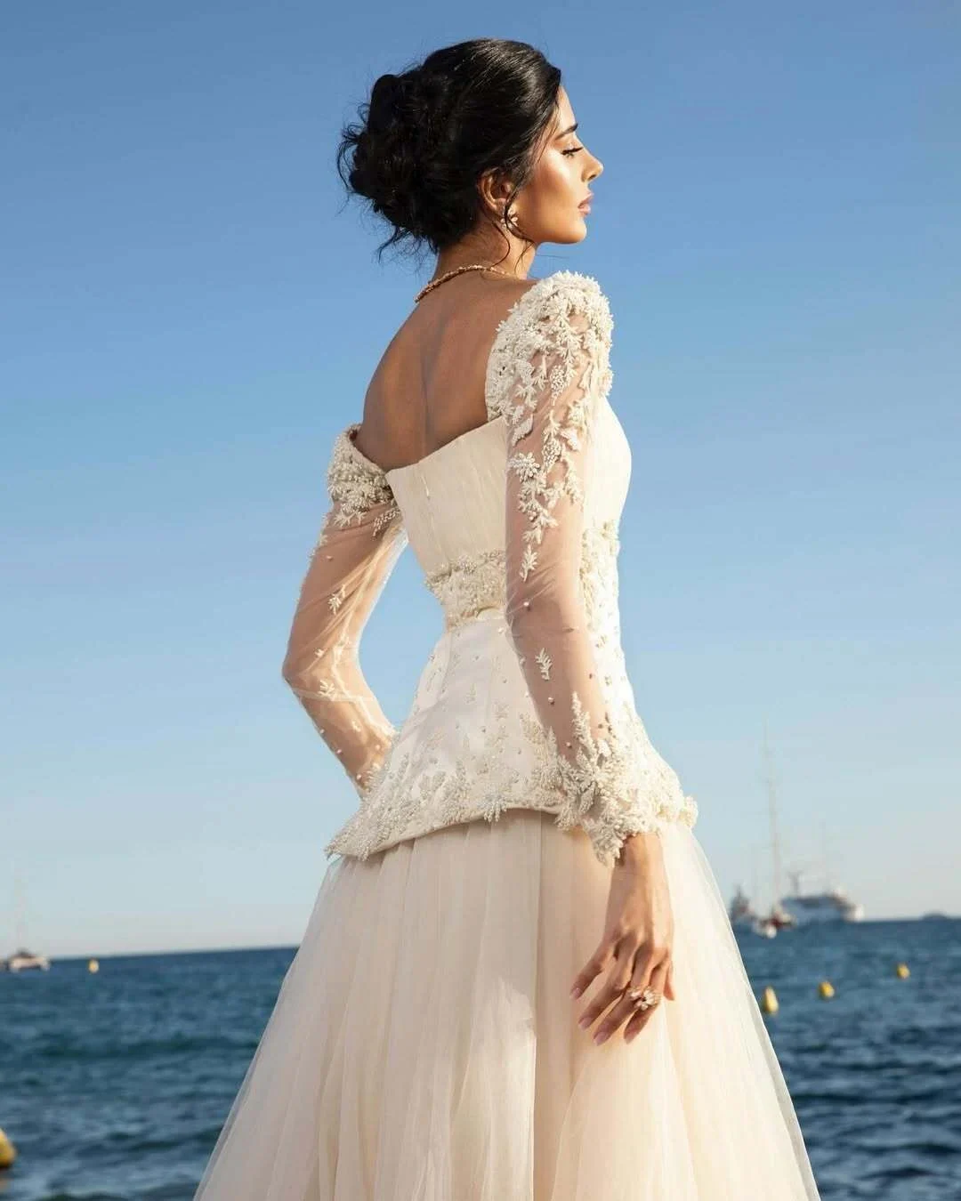 Rahaf beside the water in Cannes in an embroidered ivory gown